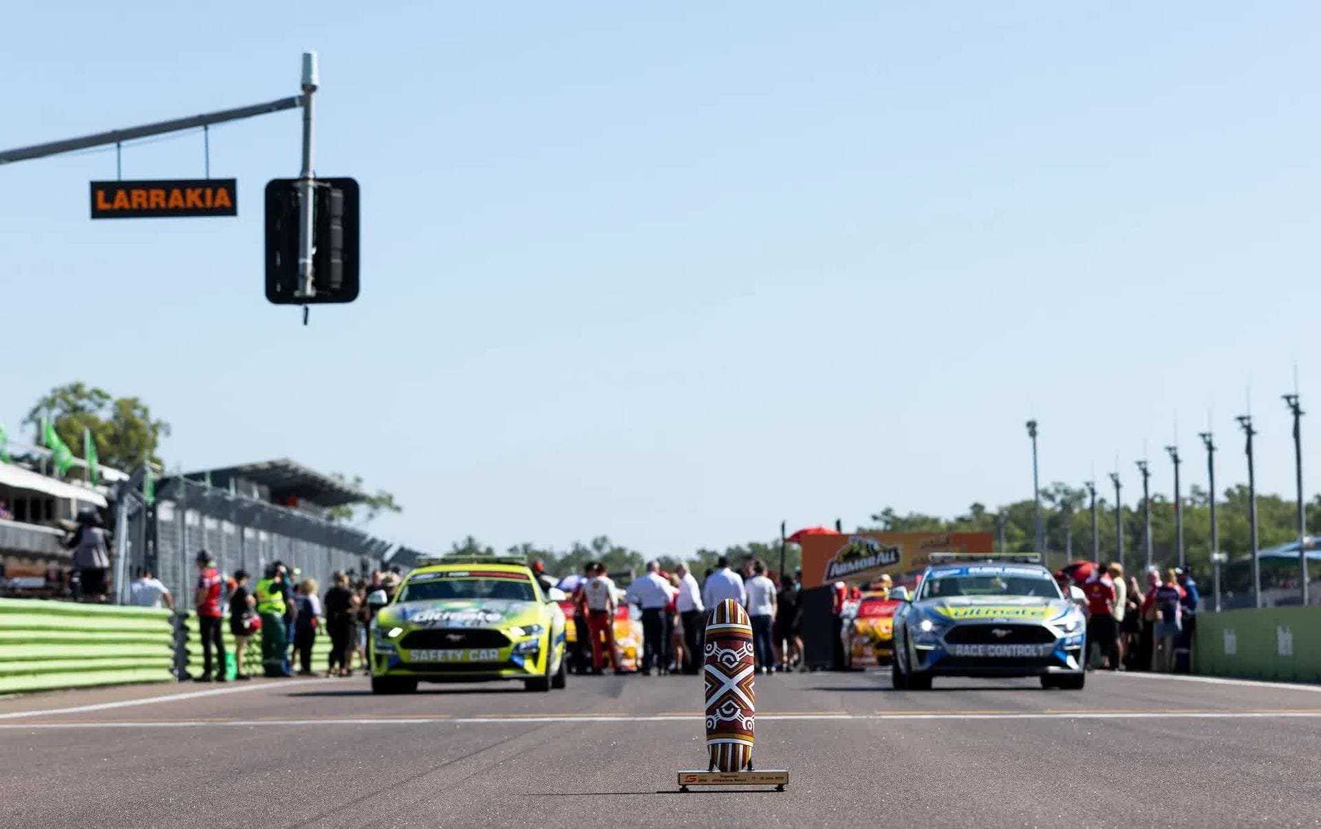 The Triple Crown Trophy on the starting grid with safety cars and crowd in background